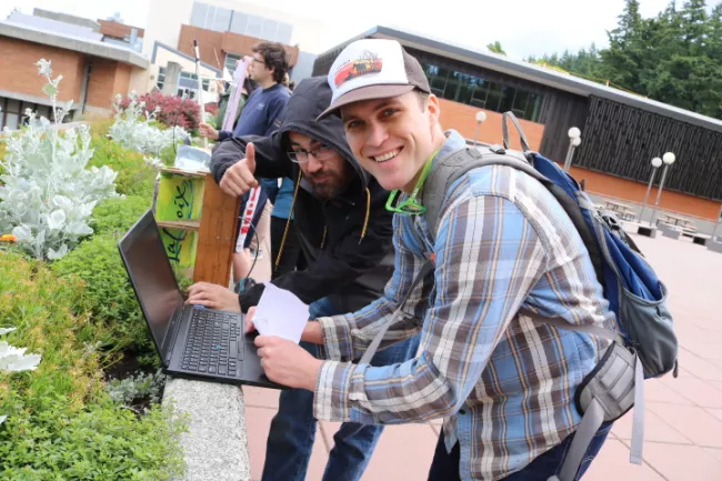 Two EECE students working outside and smiling at the camera