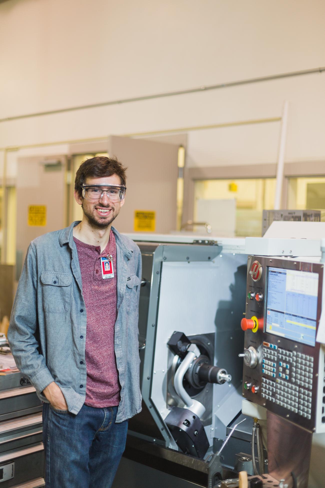 A Manufacturing Student standing next to a machine