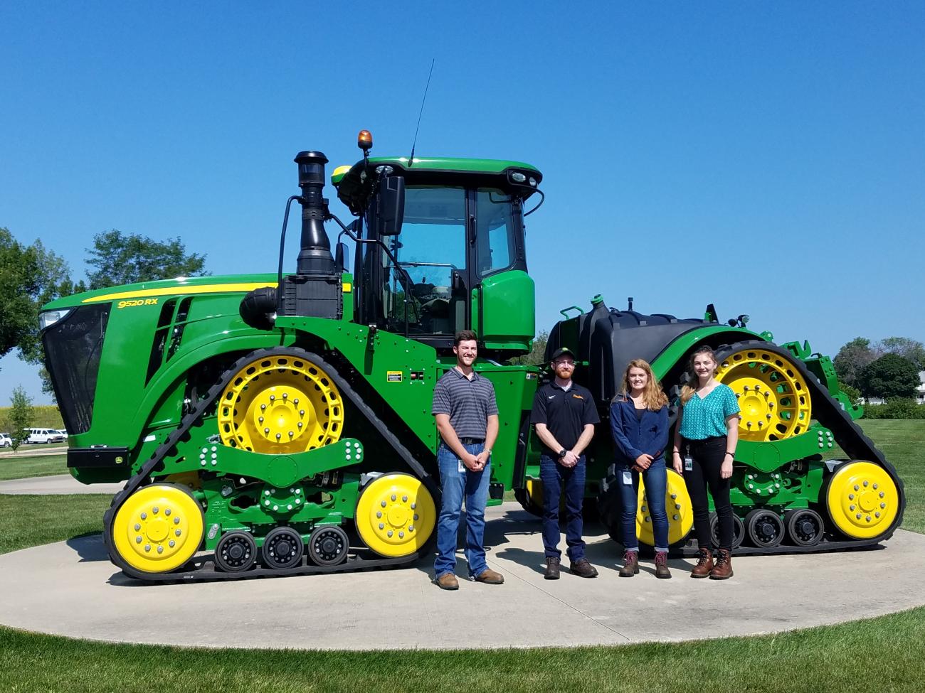 An image of a senior project group standing in front of a tractor for their project
