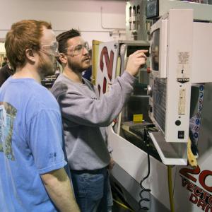 two stduents working on a machine